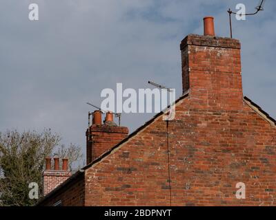 View of chimney pots and TV aerials from one end of building. In Westbury, Wiltshire, UK. Stock Photo