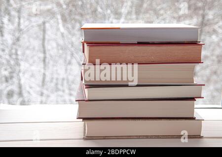 Book stack on wood desk and blurred bookshelf in the library room, education background Stock Photo