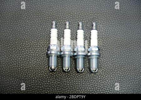 Four automotive spark plugs on a black background Stock Photo