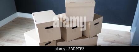 Pile of carton boxes standing in the middle of empty room in new house Stock Photo