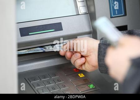 Male hands holding bunch of hundred dollars banknotes at atm machine Stock Photo