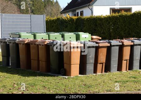 Trash cans of various colors stand in a row on the street Stock Photo