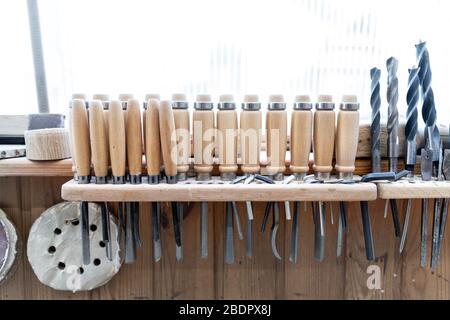 Set of woodworking tools and equipment hanged on wall at carpentry. Different chisels, drills and pencils at craftsman workshop. DIY instruments on Stock Photo