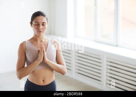 Young woman in sport bra standing with her eyes closed and relaxing she meditating during yoga Stock Photo
