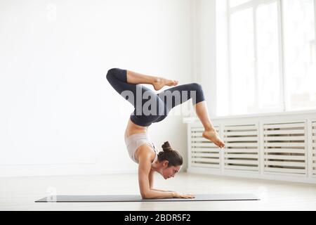 Young flexible woman doing sports exercises on exercise mat in the class Stock Photo
