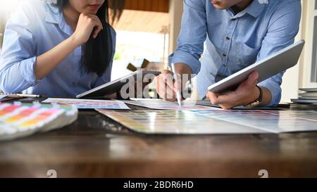 Photo of graphic designer team working together with computer tablet and color guide at the modern working table over comfortable office as background Stock Photo