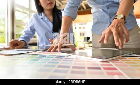 Photo of graphic designer team working together with computer tablet and color guide at the modern working table over comfortable office as background Stock Photo