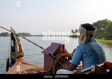 Skipper steering the Kettuvallam,house boat in the Kerala Backwaters at  Lake  Vembanad, India Stock Photo