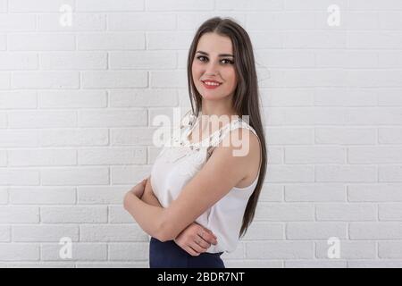 A portrait of a beautiful young businesswoman, secretary or student wearing white formal shirt black skirt, smiling looking at you, isolated white bri Stock Photo