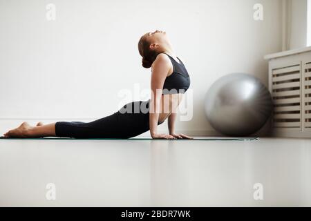 Young woman doing stretching exercises on exercise mat during sports training in health club Stock Photo