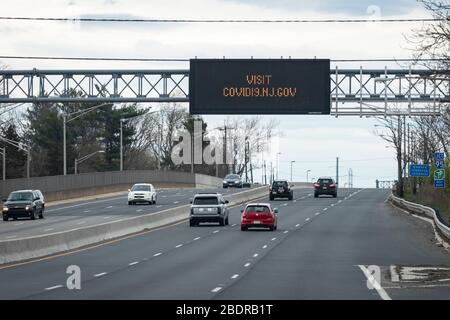 State government information website on an electronic traffic message sign, above highway and cars during COVID-19 pandemic Stock Photo
