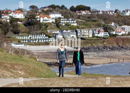 Pictured: Two women walk on the coastal path by Langland Bay near Swansea, Wales, UK. Sunday 22 March 2020 Re: Covid-19 Coronavirus pandemic, UK. Stock Photo