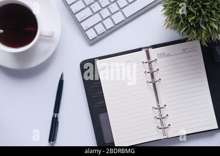 high angle view of open diary, tea and keyboard on office desk. Stock Photo
