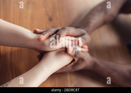 Love, family, support, friendship. Close up of african-american male and caucasian female hands holding. Concept of relationship, trust and confidence, helping hand, tenderness and warm. Stock Photo
