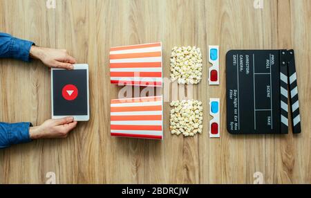 Man watching movies streaming online using a digital tablet, popcorn, 3D glasses and clapboard, cinema and entertainment concept Stock Photo
