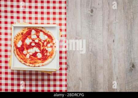 Pile of pizza boxes on a checked tablecloth and tasty pizza on top, take away food concept Stock Photo