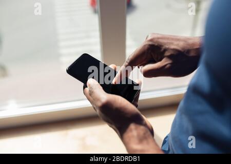 Using smartphone. Close up of african-american male hands, working in office. Concept of business, finance, job, online shopping or sales. Copyspace for advertising. Education and freelance. Stock Photo