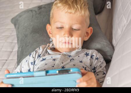 Caucasian baby boy using digital tablet while lying on bed at home Stock Photo