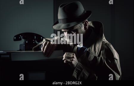 Vintage undercover criminal spy stealing files in a filing cabinet late at night, security and data theft concept Stock Photo