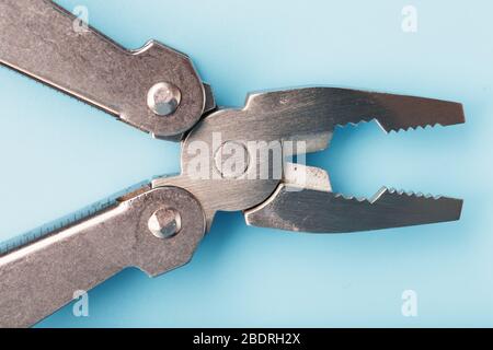 Multifunctional tool close-up on a blue background. The concept of a pocket tool with free space. Stock Photo