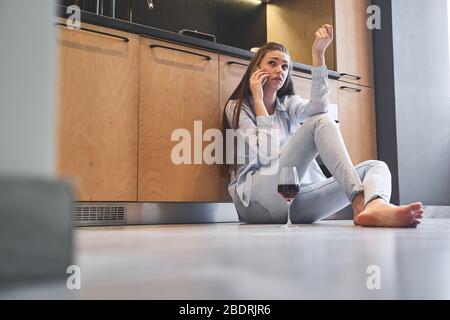 Serious girl with a gadget sitting on the floor Stock Photo