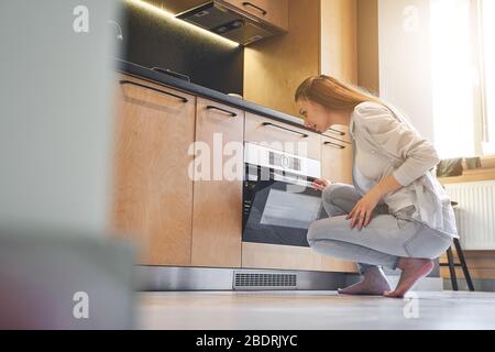 Housewife sitting on her haunches in the kitchen Stock Photo