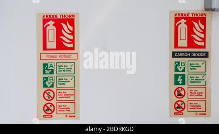 Fire extinguisher sign on red background in white wall. Stock Photo