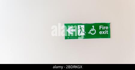 A neon green exit sign plate with a disabled, man figure and arrow to the door as an instruction for directions in case of an emergency Stock Photo