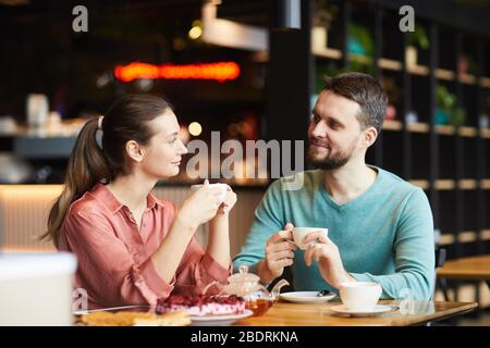 Young affectionate couple looking at each other and drinking tea at the table at the restaurant Stock Photo
