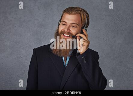 Male operator. Handsome young man portrait in formal wear and headset looking side wards and smiling while standing isolated on white background. Stud Stock Photo
