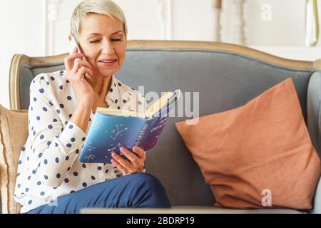 Contented elderly lady holding an astrology book Stock Photo