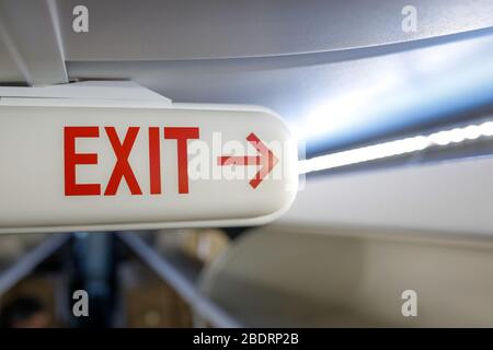 Shallow depth of field image (selective focus) with the exit sign on the ceiling of a commercial airplane. Stock Photo