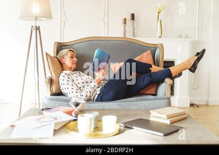 Aged female astrologer lying on a sofa Stock Photo