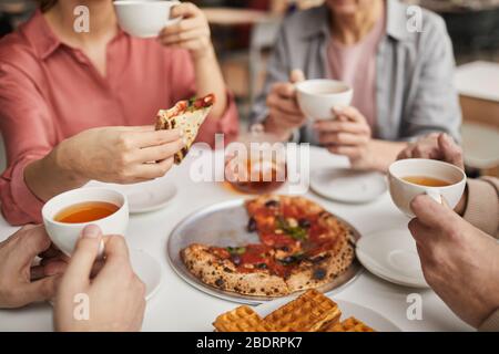 Close-up of woman holding piece of pizza and having lunch together with her family at the table Stock Photo
