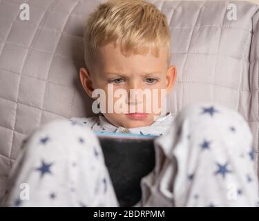 Caucasian kid boy using digital tablet while lying on bed at home Stock Photo