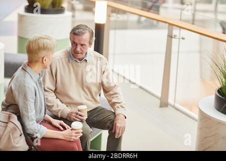 Mature couple resting after shopping they sitting and drinking coffee in the mall Stock Photo
