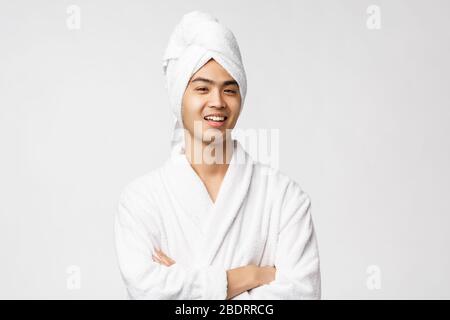 Beauty, spa and leisure concept. Portrait of handsome funny asian man relaxing at home, making himself comfortable wearing bathrobe and bath towel Stock Photo