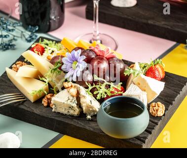 cheese platter with parmesan cheddar white and blue cheese nuts and honey Stock Photo