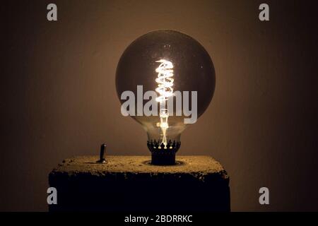 Large light bulb shining on homemade concrete lamp Stock Photo