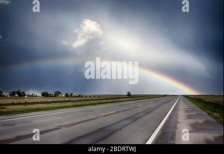 Rainbow over a road in Eastern Colorado Stock Photo
