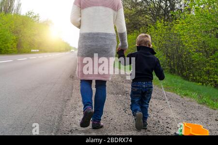Morning walk. The child with his mother walking along the road to sunrise.