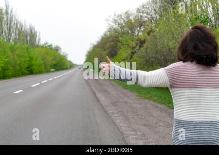 Woman hitchhiking. Back view. Stock Photo