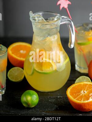 a jug of citrus beverage with orange and lime slices Stock Photo