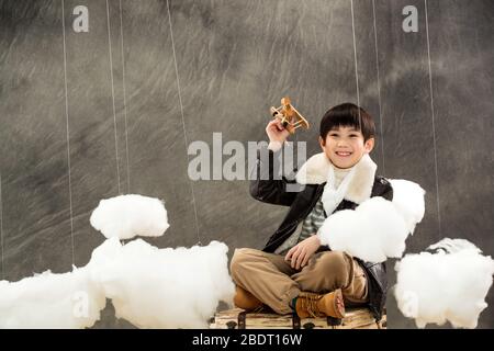 Holding a model plane boy sitting on the suitcase Stock Photo