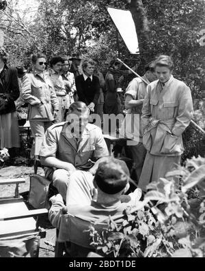 CLARK GABLE GRACE KELLY and Director JOHN FORD (back to camera) on set location candid during filming in Africa for MOGAMBO 1953 screenplay John Lee Mahin play Wilson Collison Metro Goldwyn Mayer Stock Photo