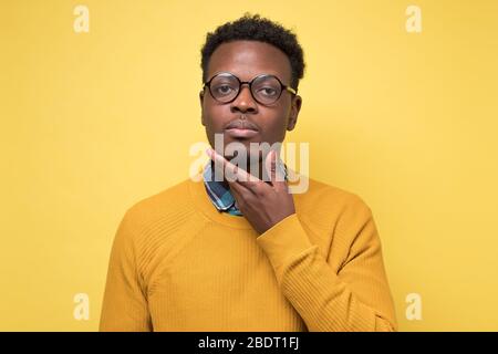 Handsome pensive afro american man in yellow clothes looking and thinking Stock Photo