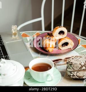 close up to round table with chocolate croissant tea cup  notebook and bag Stock Photo