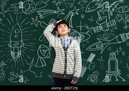 The little boy standing in front of the blackboard Stock Photo