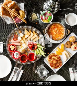 top view of breakfast table with egg dish jams cheese sausages pancakes Stock Photo