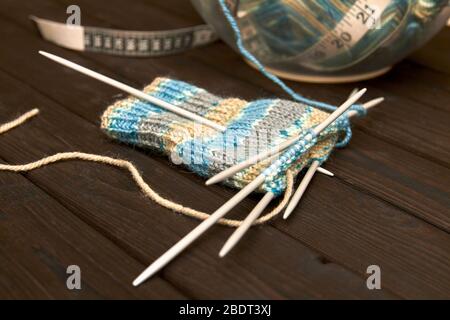 Sock in the process of knitting on dark wooden background. Closeup, selective focus Stock Photo